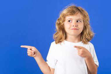 Çocuk, mavi izole edilmiş stüdyo geçmişine işaret ediyor. İşaret parmağı olan çocuk, kopyalama alanı
