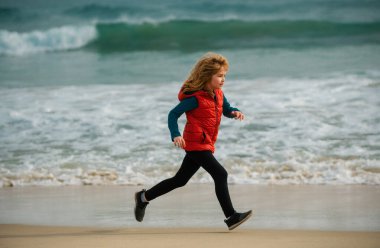 Sportif çocuk doğada koşuyor. Mutlu çocuk denize koşuyor. Çocuk sahilde eğleniyor, deniz havuzu işletiyor. Aktif aile hayatı, çocuklar açık deniz sporları.