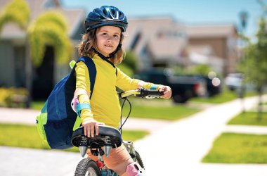 Küçük çocuk yaz parkında bisiklet sürüyor. Çocuk dışarıda bir garaj yolunda bisiklet sürüyor. Şehirde kask takan bisikletli bir çocuk. Bisikletli çocuk dışarıda. Amerikan mahallesinde bisiklet süren bir çocuk.