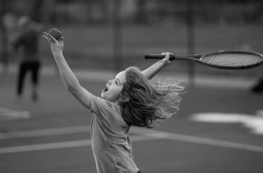Sahada tenis oynayan çocuk. Küçük çocuk tenis raketiyle tenis topuna vurdu. Çocuklar için aktif egzersiz. Çocuklar için yaz etkinlikleri. Çocuk tenis oynamayı öğreniyor. Sport Kid topa vuruyor.