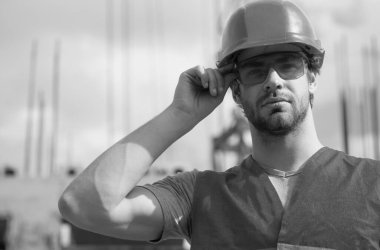 Miğferli işçi inşaat alanında poz veriyor. Geliştirme ve yenileme. Zalim bir insan müteahhidi. Üniformalı mühendis.