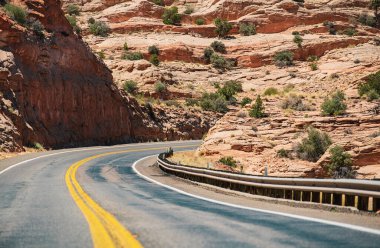 Yüksek kayalıklara karşı yol. Asfalt yolu ile doğal Amerikan manzarası