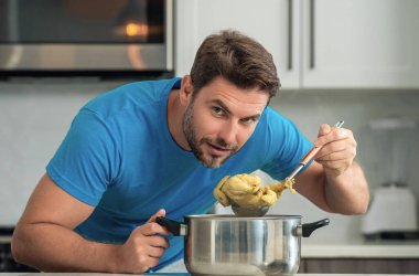 Adam mutfakta yemek pişiriyor. Şef aşçı tencereli bir yemek hazırlıyor. Menü tarifi sağlıklı yemek. Evde yemek pişiren adam mutfakta yemek hazırlıyor. Olgun bir adam mutfakta yemek hazırlıyor.