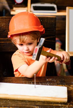 Turuncu kasklı çocuk. Alet yapımı. Erkek çekiç sesi. Çocuk çekiç çakıyor.