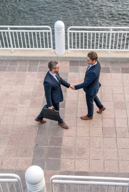 Selamlaşmak için şehirdeki eşinizle tokalaşın. Takım elbiseli işadamları dışarıda el sıkışıyor. İki işadamı arasında tokalaşma. İki iş adamının iş bağlantıları vardı. İş stratejisi