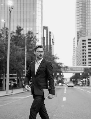 Modern şehrin merkezinde sokakta yürüyen bir iş adamı. Dışarıdaki iş adamının iş başarısı. Zarif takım elbiseli yakışıklı başarılı iş adamı.