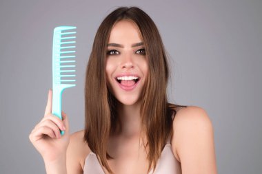 Young woman taking care with hair comb of her hair. Haircare. Pretty girl brushing hairs with comb. Beauty, hair loss products, shampoo and hair care concept