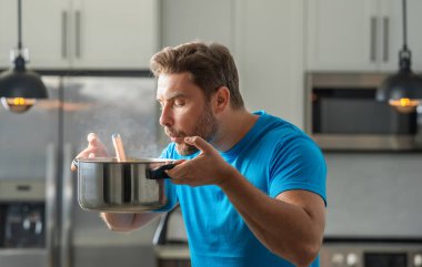 Adam mutfakta yemek pişiriyor. Şef aşçı tencereli bir yemek hazırlıyor. Menü tarifi sağlıklı yemek. Evde yemek pişiren adam mutfakta yemek hazırlıyor. Olgun bir adam mutfakta yemek hazırlıyor.