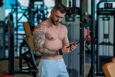 Spor salonundaki fitness adamı. Genç kaslı adam egzersizi. Seksi güçlü vücudu, gücü ve motivasyonu olan bir adam. Spor salonunda vücut geliştiren adam kaslarını şişiriyor. Fitness ve vücut geliştirme sağlığı