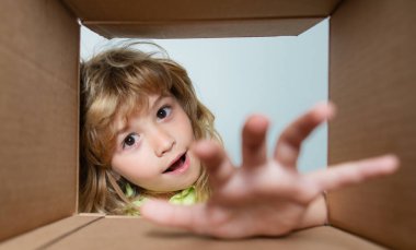 Çocuk karton teslimat kutusunu açar, paketi açar ve kapalı karton kutuyu açar. Çocuklar için kutu ve teslimat paketini aç