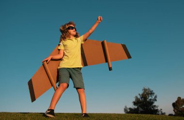 Çocukların lideri ve kazananı, başarı başlar. Heyecanlı çocuk parkta oyuncak jet kanatlı süper kahramanla oynuyor. Mavi gökyüzünde tatil gezisi