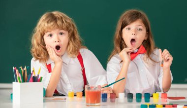 Heyecanlı okul, sınıfta renkli resimler çizen çocukları şaşırttı. Kalem kalemleriyle. Sanat ve zanaat dersinden zevk alan heyecanlı öğrencilerin portresi. Çocukluk eğitimi, çocuk sanatları.