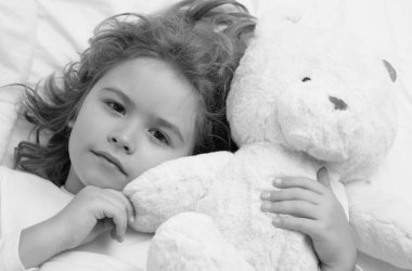 Evde oyuncak ayıyla uyuyan bir çocuk. Yatma vakti, çocuk uyuyor. Çocuk battaniyeli yumuşak yastıkta uyuyor.