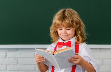 Okullu çocuk sınıfta bir kitap okuyor. Okula dönüyorum, okuldaki ilk günüm.