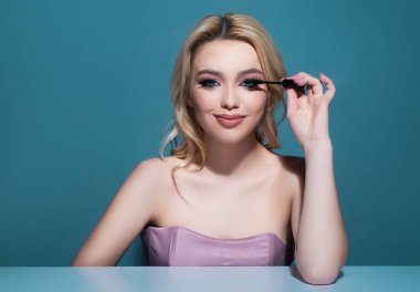 Uzun kirpikleri var. Rimel süren bir kız. Makyaj malzemeleri. Kadın güzelliği