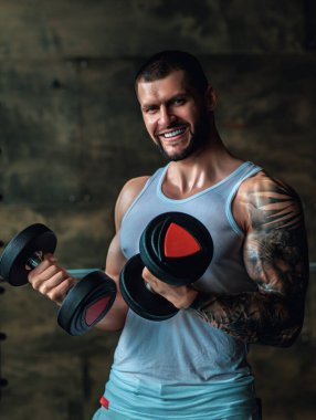 Halterle egzersiz yapan bir adam. Formda bir model ağırlık kaldırıyor, spor salonunda egzersiz yapıyor. Halterle antrenman. Güçlü, kaslı, formda, halterli ve ağır ağırlıklı bir adam. Kas pazıları için alıştırmalar