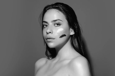 Young woman applying body cream against studio background. Beauty routine. Studio face of a beautiful woman with perfect skin. Wrinkle cream. Concept of beauty. Woman applying face cream