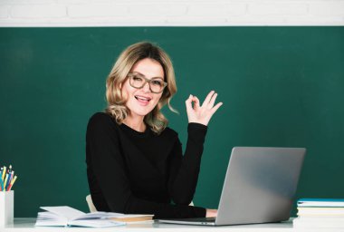 Karatahtadaki sınıfta bilgisayar bilgisayarı olan lise öğrencilerinin komik öğretmen portresi.