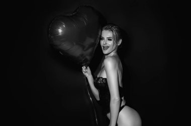 Stüdyonun arka planında kalp şeklinde hava balonu olan güzel bir kız. Sevgililer gününde bir kadın. Aşkın kalbi. Kadın modelin kalbi kırmızı balon gibidir. Tatil partisi, doğum günü. Kalp aşkı konsepti