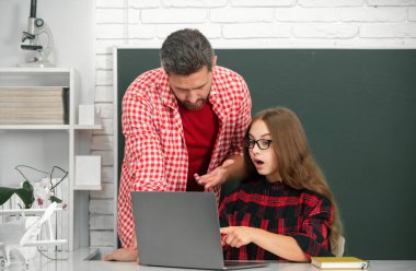 Teacher helping elementary school pupils in computer class, learning with laptop. Elementary school classroom. Teacher and schoolchild pupil in class. Teacher helping young students