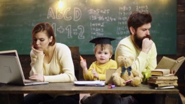 Aile okulu. Çocukların öğrenme ve eğitim konsepti. Mutlu bir aile. Anne baba ve oğul birlikte okuyorlar. İlkokuldan bir çocuk.