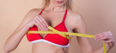 Kilo kaybı. Göğüs ölçüm bandı olan kadın model bej üzerinde izole edilmiş. Kilo kaybı ve diyet konsepti. Diyet ve kilo kaybı. Mükemmel göğüsler. Kilo kaybı ve sağlıklı yiyecekler