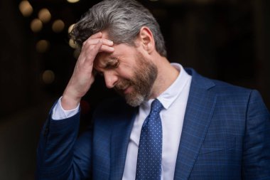 Üzgün iş adamının migreni tuttu. Güçlü baş ağrısı olan bir adam. Stresli, baş ağrısından yorgun iş adamı. Baş ağrısı, yorgunluk ve stres, migren. Baş ağrısı konsepti