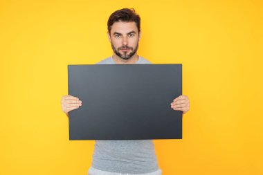 Stüdyo arka planında tanıtım panosu gösteren bir adam. Kopyalama uzayı olan boş tabela. Reklam konsepti. Fotokopi alanı olan reklam panosu, boş kopya alanı. Boş tabela, pano