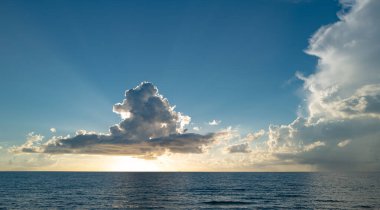 Gündoğumu denizi. Bulutların arasından gün batımını izleyen sakin bir deniz. Meditasyon okyanusu ve gökyüzü arka planı. Huzurlu deniz manzarası. Günbatımı deniz suyunun üzerinde bir ufuk. Gün batımı gökyüzü sakin