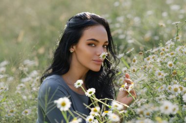 Romantik bir ruh hali. Yaz trendi tarzı, doğal görünüş. Papatya tarlasında bir kadın. Papatya tarlasındaki güzel kadın. Çekici bir kadın yaz tatilinin tadını çıkarıyor.