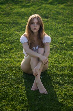 Yeşil çim tarlasında güzel, hassas, seksi genç bir kadın. Yaz doğasında güzel bir kızın portresi. Genç bir kızla yaz çayırı. Dışarıdaki genç bayan. Yazın kaygısız kadın