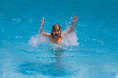 Havuza su sıçratan heyecanlı çocuk. Küçük çocuk mavi yüzme havuzunda su sıçratıyor. Havuzda yüzen ve su sıçratan tatlı çocuk. Su sıçratan ve havuz başında eğlenen çocuk