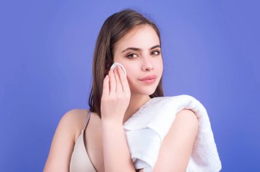 Pamuklu yastıklı kadın. Telafi için Toner. Temiz cilt, stüdyo geçmişi. Pamuk pedi tutan, yüzüne losyon süren, makyajını silen güzel bir kadın.