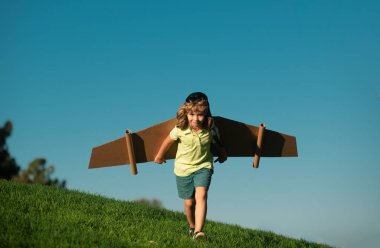 Çocuk parkta karton oyuncak kanatlarla oynuyor. Çocuk günü kavramı. Pilot kostümlü çocuk oynuyor ve havacı uzay adamı olmanın hayalini kuruyor. Çocuk özgürlüğü kavramı
