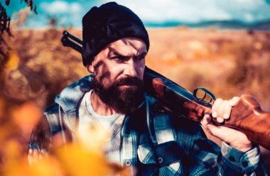 Ormanda kaçak avcı. Sakallı avcı silah tutuyor ve ormanda yürüyor. Av ruhsatı. Avlanan av tüfekli avcı