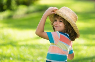 Doğa parkında neşeli bir çocuğun portresi. Sevimli, neşeli küçük çocuk. Hasır şapkalı komik çocuk portresini kapat. Yaz tatili