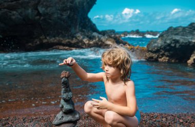Çocuk ve taş kule okyanusa yakın. Mükemmel meditasyon için kumsalda Zen taşları. Deniz çakıl kulesi. Sakin olun. Çocuklar sakinleştirme tekniği.