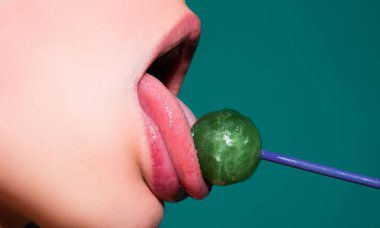 Kadın ağzında lolipop, kırmızı ruj. Kırmızı, parlak bir lolipopu yalayan bir kadın. Kapatın. Şehvetli ağzında lolipopu olan seksi kadın.