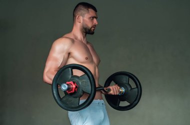 Muscular man lifting weights at gym. Handsome guy prepare to do exercises with dumbbell