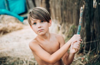 Samanlıkta yatan neşeli bir çocuğun portresi. Çocuk sonbahar için çocuk kıyafetleri reklamı yapıyor. Sonbahar festivalinde mutlu bir çocuk. Köyde rahim tatili yapan tatlı bir çocuk. Küçük çocuk doğal ürünlerin reklamını yapıyor.