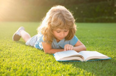 Zeki zeki çocuklar. Dışarıda kitap okuyan sevimli bir çocuk. Çocuk parkta kitap okudu. Açık hava çocuk eğitimi