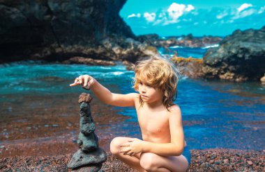Şirin çocuk deniz kıyısında taş yığıyor doğada. Okyanus sahilindeki Cairn, beş çakıl kulesi. Denge ve uyum kavramı. Sakin ve ruhlu