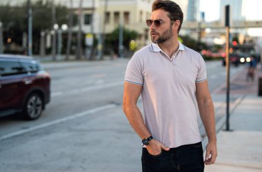 Büyük şehirde kendine güvenen yakışıklı bir adamın portresi. Sokakta poz veren sıradan giyinmiş seksi bir adam. Şehir yaşam tarzında başarılı bir erkek model. Kafkasyalı orta yaşlı adam dışarıda.
