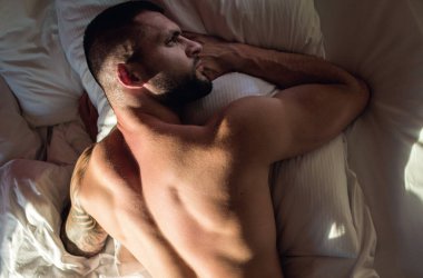 Sexy male round buttocks, Sexy shape butt. Muscular hunk. Naked man model in bed. Gay sexy model. Perfect shoulders and chest. Muscular sexy man with naked torso. Hunk with athletic body in bed