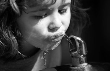 Parkta su içen küçük sarışın bir çocuğun portresi, yakın plan. Tatlı çocuk suratı. Pozitif duygusal çocuk. Susamış çocuklar.