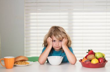 İştahsız bir çocuğun portresi. İştah kaybı kavramı. Çocuk öğle yemeği sırasında mutfakta sebze ve meyve yiyen ergen bir çocuk. Sağlıklı yemek, sebze yemeği...