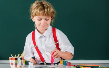 Resim ödevi yapan, elinde kalem tutan, yazı yazan okul çocuğu. Çocuk ilkokulda resim çiziyor. Çocuk sanatı, yaratıcılık çocukları