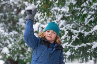 Kartopu eğlencesi. Çocuk kartopu oynuyor. Noel tatili, kış aile tatili. Çocuk Kartopu savaşının tadını çıkarıyor. Kışlık elbiseli çocuk kartopu atıyor. Kışın çocuklar, karla oynayın, kartopu yapın.