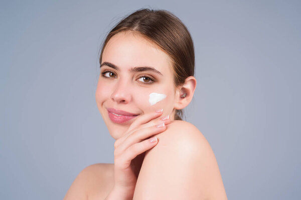 Уход за кожей. Красота портрет красивой женщины с нанесением крема для лица изолированы на фоне студии. Молодая модель использует крем для ухода за телом. Крем для лица, увлажняющий подъемный питательный крем
