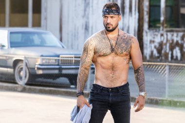 Yakışıklı hippi İspanyol modelin portresi. Sokaktaki seksi, modern adam. Moda erkeği sokak arka planında poz veriyor. Adam sokak çetesi, sosyal sorun. Suç şehri. Tehlikeli Amerikan Bölgesi